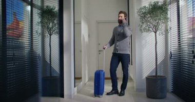 Beyaz erkek, küçük bir antrede taksi bekliyor. Akıllı telefondan arkadaşınla ya da akrabanla sohbet ediyorsun. Bavul yanında duruyor. Tatile ya da iş gezisine hazırım..