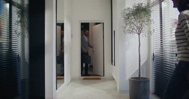 İşten eve dönen, kurye çantalı yakışıklı, beyaz erkek. Bir elinde kurye çantası taşıyor. Kadın, çalışkan adamı dairede selamlıyor. İşten sonra akşam..