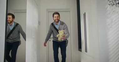 Beyaz bir adam iş gezisinden eve dönüyormuş. Küçük kızıyla selamlaşıyor. Küçük çocuk için hediye getirdim. Oyuncak ayıyı sevgili kıza vermek. Kadın kocasına sarılıyor..