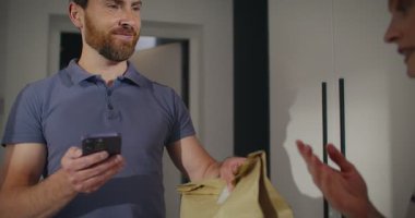 Beyaz kadın, yakışıklı teslimatçıya ön kapıyı açıyor. Erkek, sıcak yemek dağıtırken kadın telefonunu bazı bilgilerle gösteriyor. Kız emri onaylıyor. Yemek teslimatı..