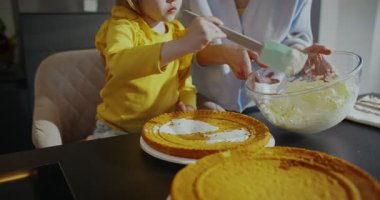 Güzel beyaz bir kadının itaatkar çocuğuyla vakit geçirmesini gösteren kamera görüntüsü. Mutfakta lezzetli turta pişirirken aile iletişimi. Küçük çocuk annesine tatlı hazırlamasında yardım ediyor..
