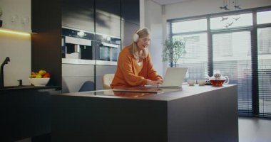 Güzel beyaz kadın mutfağın ortasında oturuyor. Metin veya bilgi giriliyor. İnternetten tarif arıyorum. Mesaj yazarken yeni kulaklık takıyor. Müzik ya da video dinlerken.