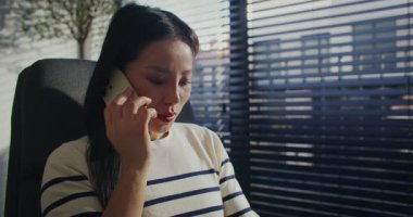 Güzel Çinli kız aktif olarak akıllı telefondan konuşuyor. Büyük pencerelerin yanındaki sandalyede rahatça oturabilirsin. Uzak muhabbet ediyoruz. Ofiste ya da rahat bir odada uzaktan iletişim kurmak..