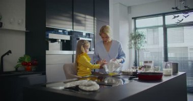 Önemseyen beyaz bir anne, küçük kızının ellerini temizlemesine yardım ediyor. Beyaz havluyla siliyorum. Ev hanımı küçük çocukla akşam yemeği hazırlıyor. Ebeveynle pişirme ya da kızartma için hazırlanılıyor.