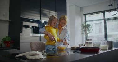 Sıcak aile anının yan görüntüsü. Anne ve kızı birlikte çalışıyor. Özel bir şeyler pişirmeyi planlıyorum. Mutfak eşyalarıyla uğraşırken birbirleriyle konuşup gülümsüyorlar. Pişirme ya da pişirme.