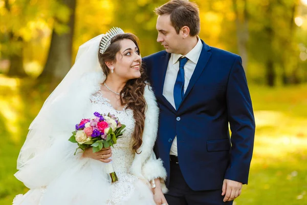 Yeni evliler parkta yürürler ve bir fotoğrafçıya poz verirler.