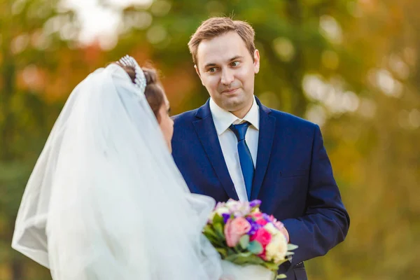 Recém-casados caminham no parque e posam para um fotógrafo — Fotografia de Stock