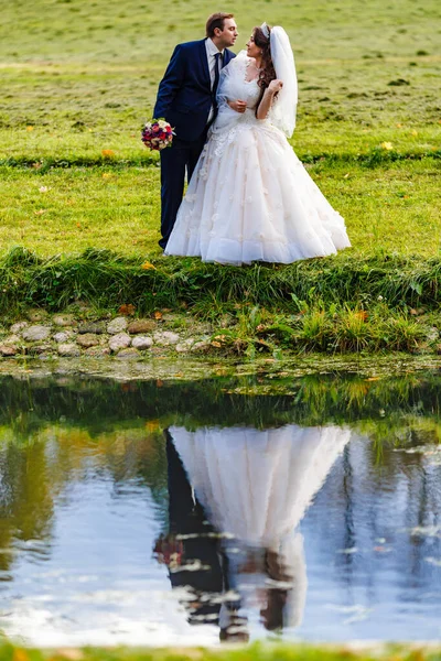 Recém-casados caminham no parque e posam para um fotógrafo — Fotografia de Stock