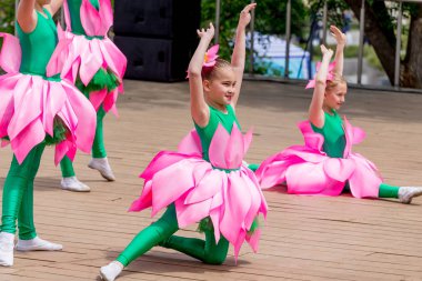 Rusya, Vladivostok, 06/12/2018. Lotus çiçek komik kostümleri güzel küçük kız sahnede dans gerçekleştirin. Haziran 12 yıllık Rusya günü kutlaması. Çocukların performans. Gösteri ve performans.
