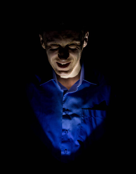 Stylish dark portrait of adult caucasian man who seems like maniac or psycho. Isolated on black background. Low-key lighting.