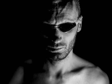 Tıraşsız yetişkin beyaz adam gözlük yüzme portresi. O manyak gibi gülümser ve delilik ya da deli gibi görünüyor. Siyah ve beyaz çekim, düşük anahtar aydınlatma. Siyah izole.