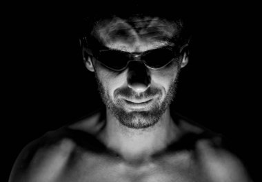 Tıraşsız yetişkin beyaz adam gözlük yüzme portresi. O manyak gibi gülümser ve delilik ya da deli gibi görünüyor. Siyah ve beyaz çekim, düşük anahtar aydınlatma. Siyah izole.