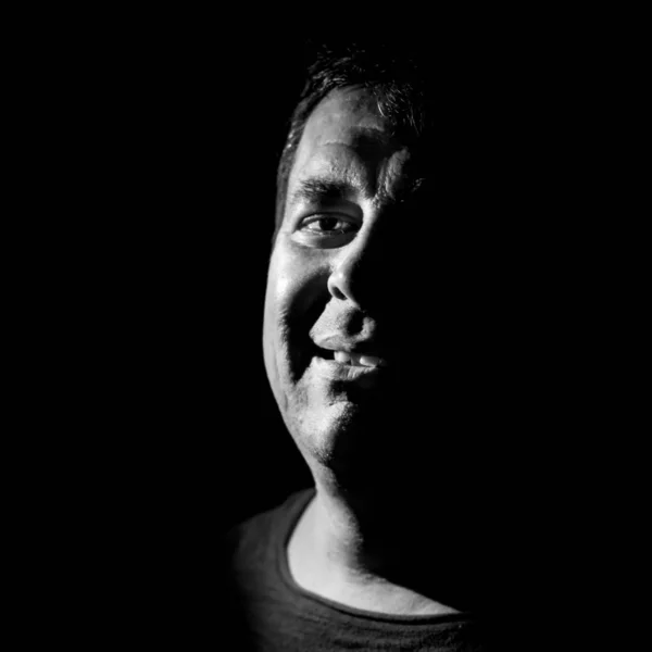 stock image Stylish portrait of adult caucasian man. He smiles like maniac and seems like maniac or crazy. Black and white shot, low-key lighting. Angry man, fear concept. Isolated on black.