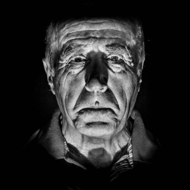 Yaşlı ve üzgün beyaz bir adamın portresi. Siyah beyaz çekim, düşük tuşlu ışıklandırma. Siyah üzerinde izole.