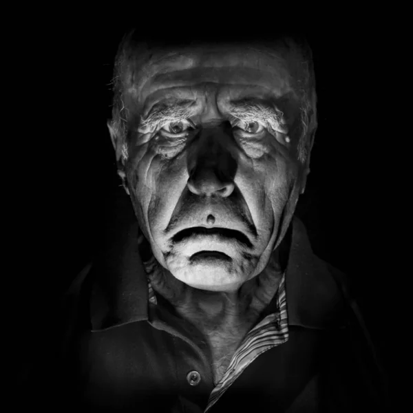 Portrait of old and sad caucasian man. Black and white shot, low-key lighting. Isolated on black.
