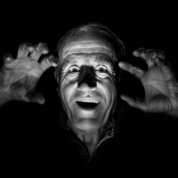 Portrait of old caucasian man who scares watcher. Fear and scare concept. Black and white shot, low-key lighting. Isolated on black.