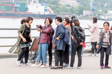 Rusya, Vladivostok, 07/06/2019. Güney Kore'den gelen bir grup turist şehir merkezindeki turistik mekanlarda fotoğraf çekiyor. Vladivostok Turizm, Asyalı turistler, şehrin manzaraları yürüyüş.