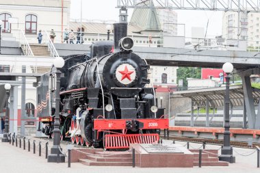 Russia, Vladivostok, 07/06/2019. Old train locomotive as monument on the platform of railway station Vladivostok. This monument is in memory of railway workers who worked during Second World War. clipart