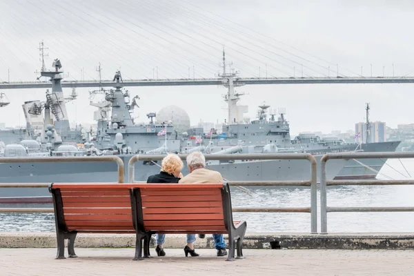 高齢の観光客のカップルは 都市のダウンタウンでロシア太平洋艦隊の軍艦と港の景色を賞賛します ロシア ウラジオストク — ストック写真