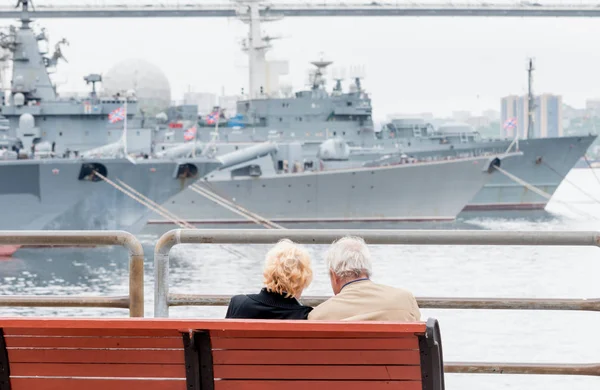 高齢の観光客のカップルは 都市のダウンタウンでロシア太平洋艦隊の軍艦と港の景色を賞賛します ロシア ウラジオストク — ストック写真