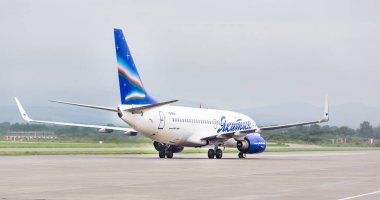 Rusya, Vladivostok, 08 / 21 / 2019. Yakutia Havayolları 'ndan (Rusya) Boeing 737-700 sefer sayılı yolcu uçağı bulutlu bir günde havaalanına indi. Havacılık ve ulaşım.