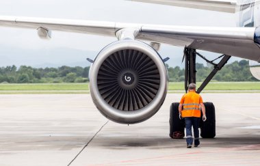 Mühendis pistteki modern yolcu uçağının şasesini kontrol ediyor. Uçakların bakımı ve bakımı. Havacılık ve ulaşım.