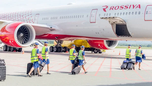 Rusya, Vladivostok, 08 / 17 / 2020. Rossiya Havayolları resmi üniformalı uçak mürettebatı uçağa biner. Arka planda Rossiya Havayolları 'ndan Boeing 777 uçağı yer alıyor. Havacılık ve ulaşım.