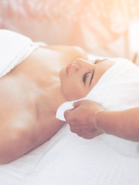 Spa yatağında uzanan rahat genç bir kadın lüks bir spa merkezinde yüz bakımı ve masaj için hazırlandı. Sağlık, stres atma ve gençleştirme kavramı.