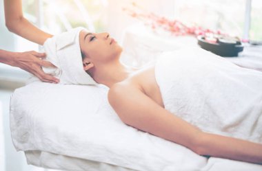 Spa yatağında uzanan rahat genç bir kadın lüks bir spa merkezinde yüz bakımı ve masaj için hazırlandı. Sağlık, stres atma ve gençleştirme kavramı.