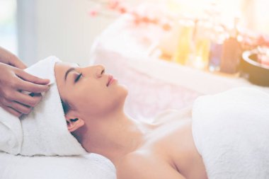 Spa yatağında uzanan rahat genç bir kadın lüks bir spa merkezinde yüz bakımı ve masaj için hazırlandı. Sağlık, stres atma ve gençleştirme kavramı.