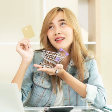 Kredi kartı evde tutan ve online mağazadan alışveriş hakkında düşünme güzel kadın. Modern online alışveriş kavramı.