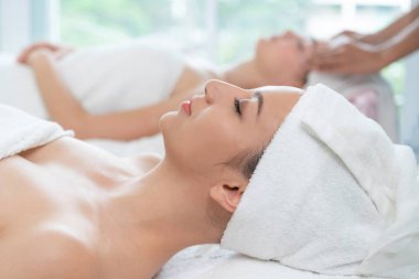 Spa yatağında uzanan rahat genç bir kadın lüks bir spa merkezinde yüz bakımı ve masaj için hazırlandı. Sağlık, stres atma ve gençleştirme kavramı.