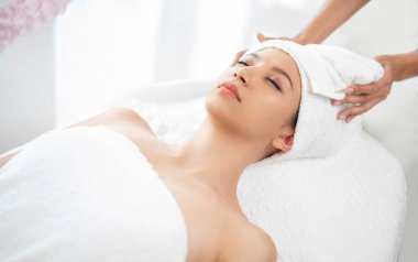 Spa yatağında uzanan rahat genç bir kadın lüks bir spa merkezinde yüz bakımı ve masaj için hazırlandı. Sağlık, stres atma ve gençleştirme kavramı.