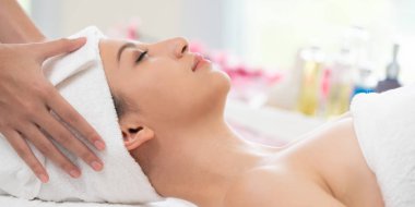 Spa yatağında uzanan rahat genç bir kadın lüks bir spa merkezinde yüz bakımı ve masaj için hazırlandı. Sağlık, stres atma ve gençleştirme kavramı.