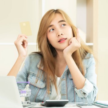 Kredi kartı evde tutan ve online mağazadan alışveriş hakkında düşünme güzel kadın. Modern online alışveriş kavramı.