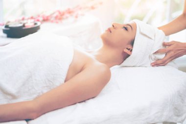 Spa yatağında uzanan rahat genç bir kadın lüks bir spa merkezinde yüz bakımı ve masaj için hazırlandı. Sağlık, stres atma ve gençleştirme kavramı.