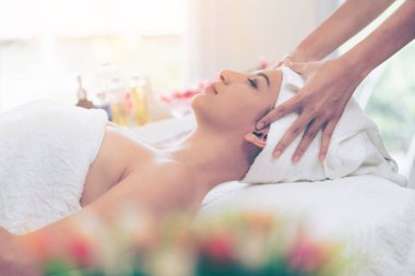 Spa yatağında uzanan rahat genç bir kadın lüks bir spa merkezinde yüz bakımı ve masaj için hazırlandı. Sağlık, stres atma ve gençleştirme kavramı.