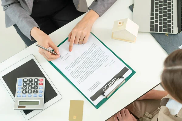 Client signs document regarding real estate activity next to lawyer or real estate agent sitting at office desk. Business concept of selling and buying house.