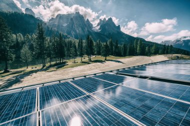 Güneşli gökyüzü ve dağ arkaplanlarına karşı kırsal alandaki güneş paneli. Güneş enerjisi, dünya enerjisinin sürdürülebilirliği için bir yeniliktir. Sürdürülebilir kaynaklar.