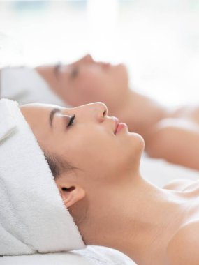 Spa yatağında uzanan rahat genç bir kadın lüks bir spa merkezinde yüz bakımı ve masaj için hazırlandı. Sağlık, stres atma ve gençleştirme kavramı.