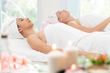 Spa yatağında uzanan rahat genç bir kadın lüks bir spa merkezinde yüz bakımı ve masaj için hazırlandı. Sağlık, stres atma ve gençleştirme kavramı.