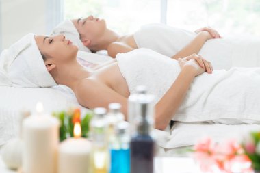 Spa yatağında uzanan rahat genç bir kadın lüks bir spa merkezinde yüz bakımı ve masaj için hazırlandı. Sağlık, stres atma ve gençleştirme kavramı.