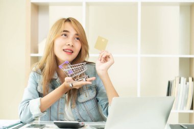 Kredi kartı evde tutan ve online mağazadan alışveriş hakkında düşünme güzel kadın. Modern online alışveriş kavramı.