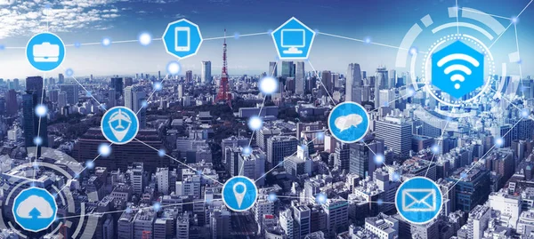 Smart city wireless communication network with graphic showing concept of internet of things ( IOT ) and information communication technology ( ICT ) against modern city buildings in the background.