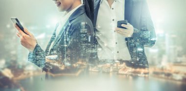 Cep telefonu ile modern şehir binaları arka plan kullanarak genç iş adamları. Gelecekteki telekomünikasyon teknolojisi ve internet şeyler (çok) kavramının.