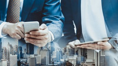 Cep telefonu ile modern şehir binaları arka plan kullanarak genç iş adamları. Gelecekteki telekomünikasyon teknolojisi ve internet şeyler (çok) kavramının.
