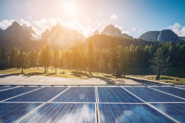 Güneşli gökyüzü ve dağ arkaplanlarına karşı kırsal alandaki güneş paneli. Güneş enerjisi, dünya enerjisinin sürdürülebilirliği için bir yeniliktir. Sürdürülebilir kaynaklar.