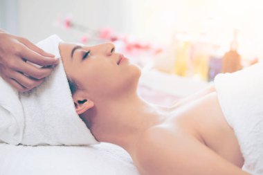 Spa yatağında uzanan rahat genç bir kadın lüks bir spa merkezinde yüz bakımı ve masaj için hazırlandı. Sağlık, stres atma ve gençleştirme kavramı.