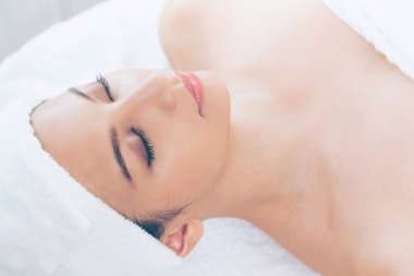 Spa yatağında uzanan rahat genç bir kadın lüks bir spa merkezinde yüz bakımı ve masaj için hazırlandı. Sağlık, stres atma ve gençleştirme kavramı.