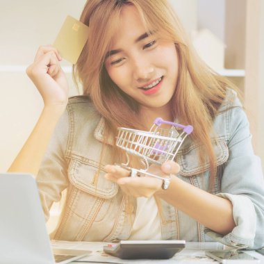 Kredi kartı evde tutan ve online mağazadan alışveriş hakkında düşünme güzel kadın. Modern online alışveriş kavramı.